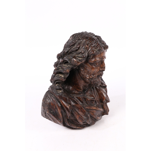 96 - A 17TH CENTURY WALNUT C ARVED BUST OF CHRIST. Flowing curled hair above wearing robes, 37cm high.