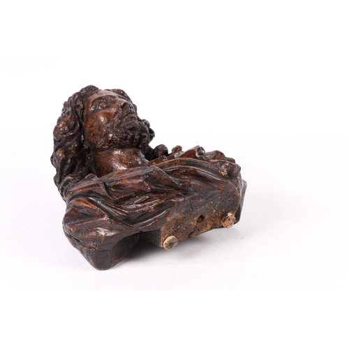 96 - A 17TH CENTURY WALNUT C ARVED BUST OF CHRIST. Flowing curled hair above wearing robes, 37cm high.