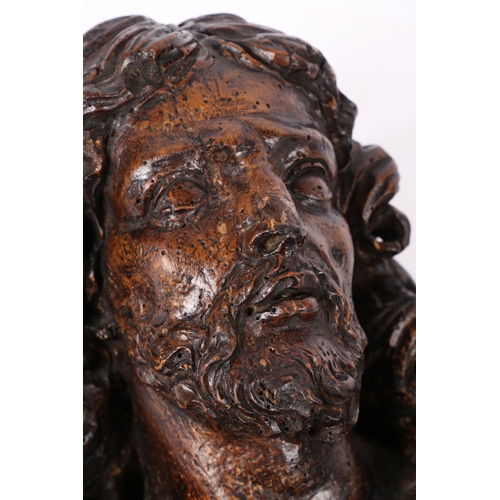 96 - A 17TH CENTURY WALNUT C ARVED BUST OF CHRIST. Flowing curled hair above wearing robes, 37cm high.