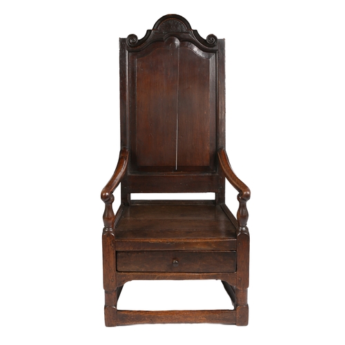 20 - A 17TH CENTURY OAK ARMCHAIR. The arched top rail above a fielded panel back and a solid seat flanked... 