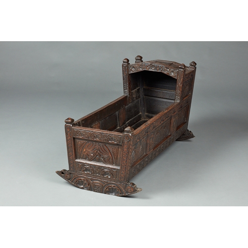 27 - A RARE AND HIGHLY UNUSUAL JAMES I OAK CRADLE, CUMBRIA, DATED 1611. The hooded cradle surmounted by f... 