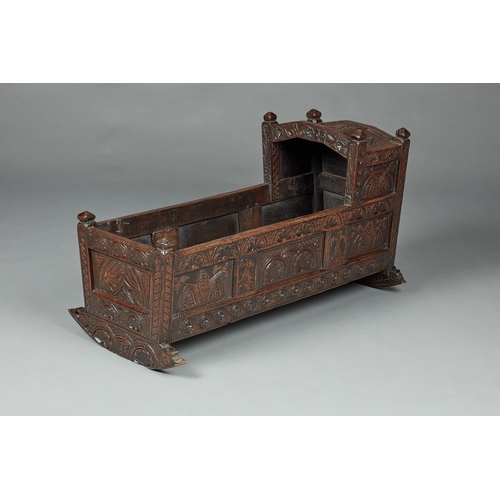 27 - A RARE AND HIGHLY UNUSUAL JAMES I OAK CRADLE, CUMBRIA, DATED 1611. The hooded cradle surmounted by f... 