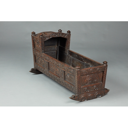 27 - A RARE AND HIGHLY UNUSUAL JAMES I OAK CRADLE, CUMBRIA, DATED 1611. The hooded cradle surmounted by f... 