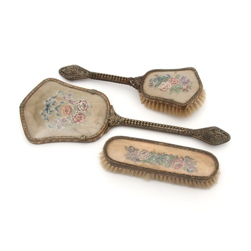 64 - A BRONZE BACKED HAND MIRROR, COMB AND BRUSH SET