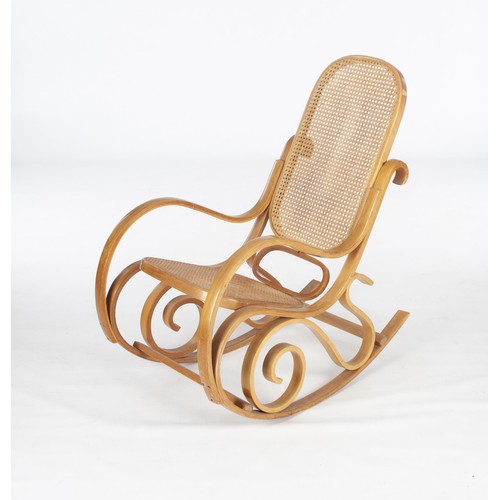 392 - A BLONDE WOOD AND CANED ROCKING CHAIR