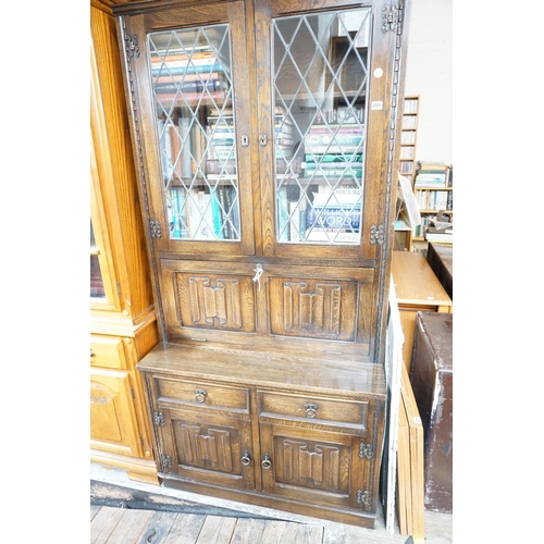 231 - A linen fold patterned oak and leaded glazed drinks cabinet with shelved and mirrored compartment ov... 