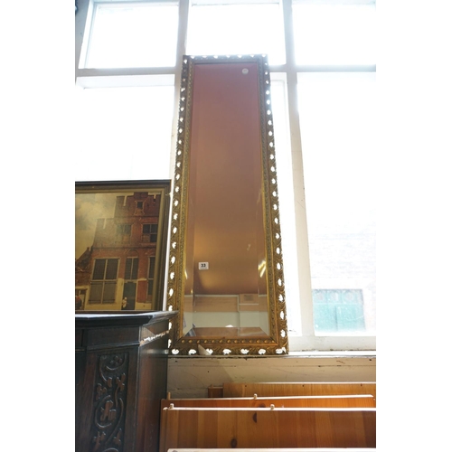 33 - A decoratively framed bevel edge mirror