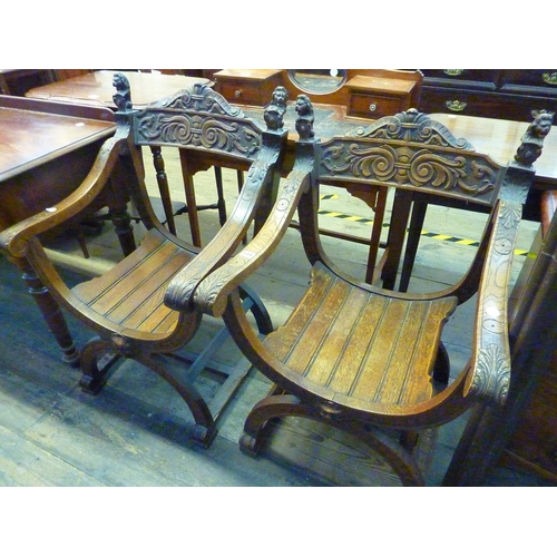 144 - A pair of oak armchairs with curved seats, carved back stretchers finishing in Lions, arched legs