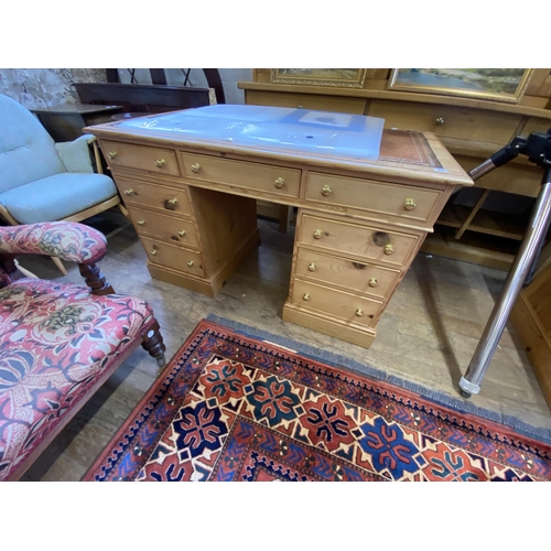 15 - A pine kneehole desk with leather inlay to the top and brass knobs