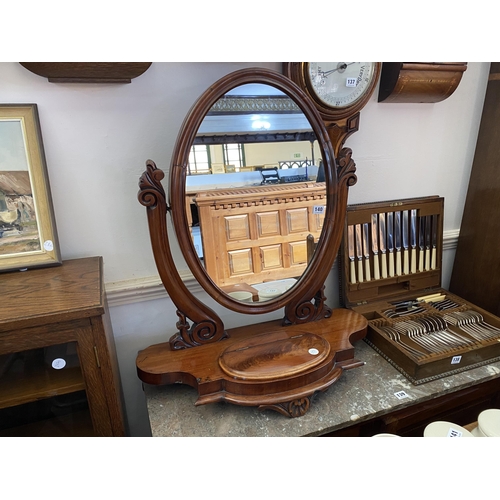 140 - A Victorian mahogany oval swing mirror with a lidded compartment to the base