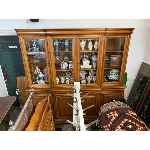 185 - A large breakfront display cabinet with bevelled glass doors about lower panelled cupboards, cushion... 