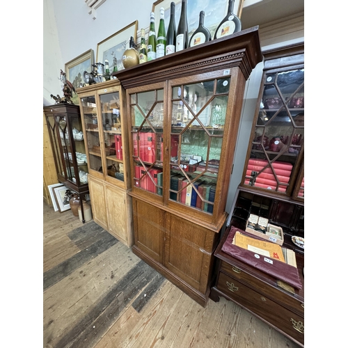 75 - An oak glazed bookcase cabinet above a double cupboard base with dental moulding, astragal glazing a... 