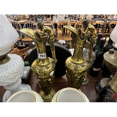 752 - A pair of 20th century brass ewers decorated with Neo classical figures with mask handles