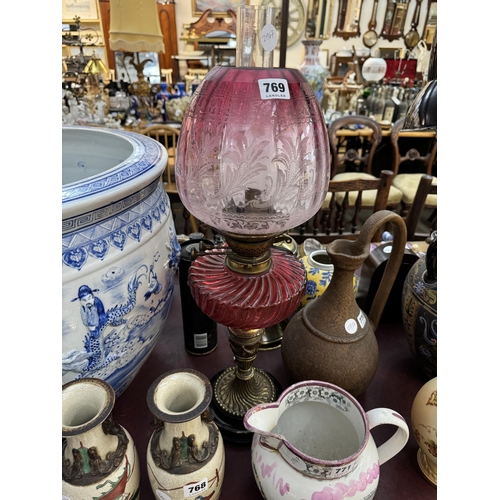 769 - A Victorian oil lamp with a classical style column, cranberry glass reserve and an etched globe