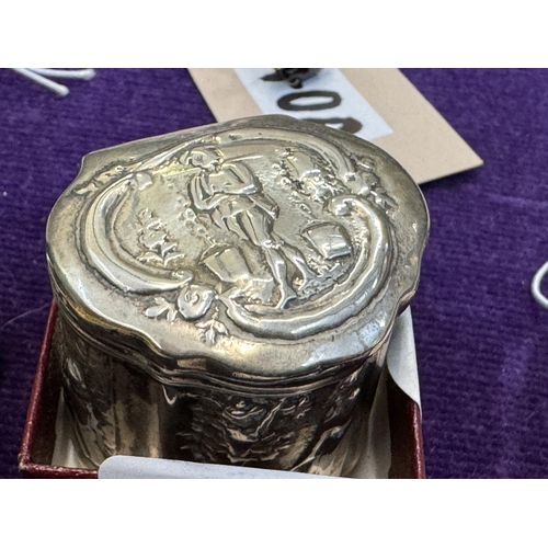 841 - A silver pill pot depicting scenes and with a hinged lid