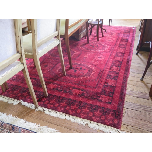 103 - An Afghan style carpet, the all over red design with medallions of stylised creatures and pendant ta... 