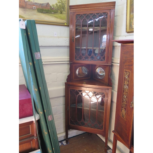 82 - An Edwardian mahogany and satinwood crossbanded corner cabinet, the glazed door enclosing velvet cov... 