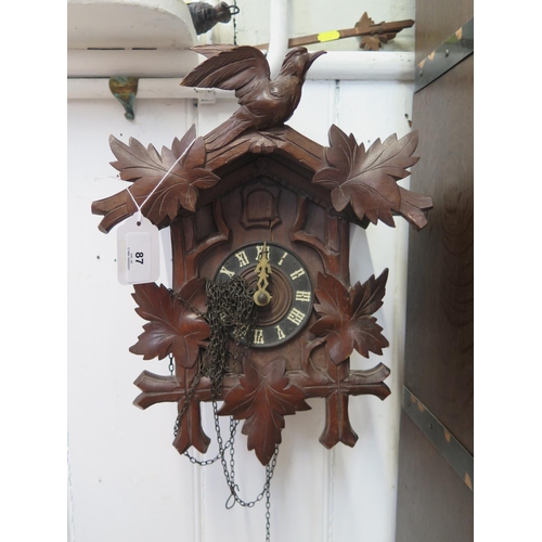 87 - A carved softwood Swiss cuckoo clock, the twin train movement with bellows and coil gong, retail lab... 