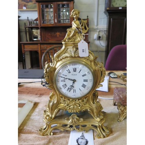 95 - A French gilt metal mantel clock case, the putti playing a harp over foliate scrolls and flaming tor... 