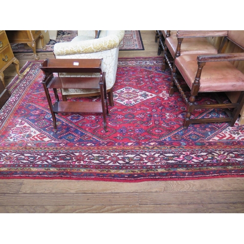 83 - A Persian Sarouk village carpet, the ivory medallion on a red ground filled with serrated medallions... 