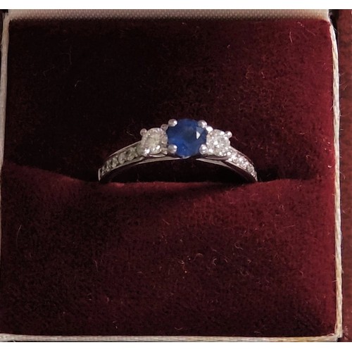 509 - A white colour metal ring set with 55-point centre sapphire and 6-side diamond, two larger diamond t... 