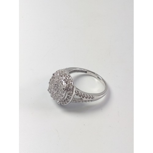 1067 - A diamond cluster ring set in 9ct white gold, with split shoulders. R/C diamonds 1.00ct. Size N.