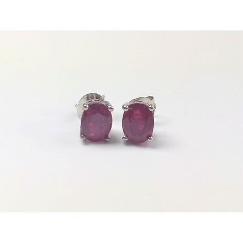 1079 - A pair of treated ruby studs in silver.