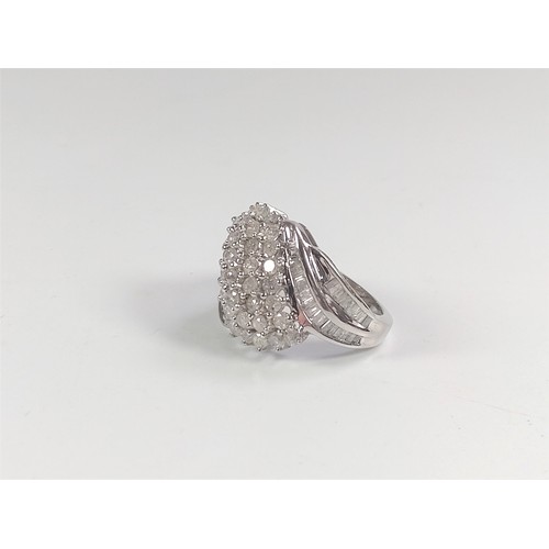 1059 - A 9ct white gold cluster ring set with Round Brilliant Cut and baguette-cut diamonds totalling 2.04c... 