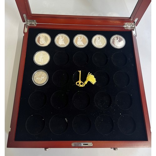 443 - A glazed specimen box containing seven fine silver proof coins.