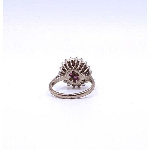 309 - An 18ct white gold, diamond, and ruby cluster ring, set with a round brilliant-cut diamond measuring... 