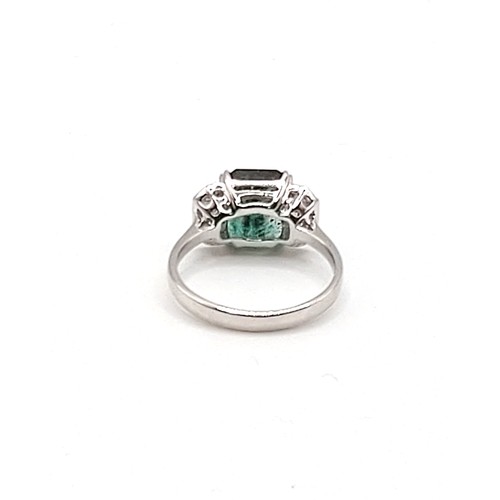 302 - An 18ct white gold, diamond, and emerald ring, in Art Deco taste, set with a mixed emerald-cut emera... 