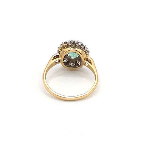 296 - An 18ct yellow gold, diamond, and emerald cluster ring, set with a mixed oval-cut emerald of approxi... 