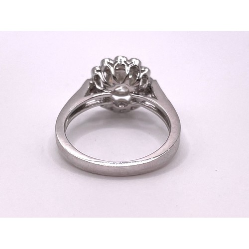 300 - An 18ct white gold and diamond halo cluster ring, centered with a round brilliant-cut diamond of app... 