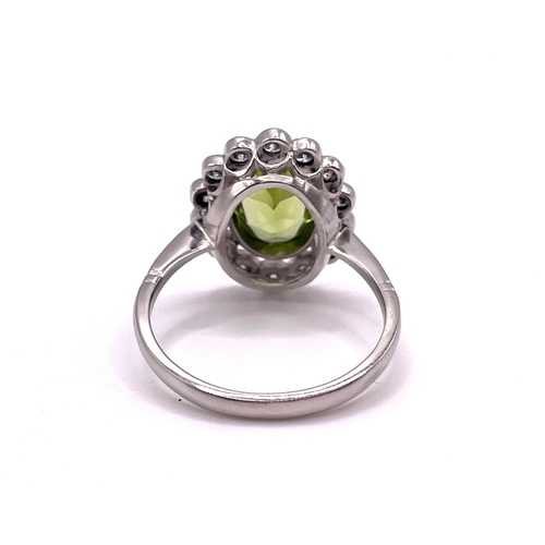 302 - A platinum, diamond, and peridot cluster ring, set with a mixed oval-cut peridot of approximately 1.... 