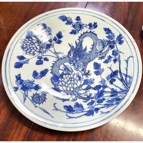 123 - An Oriental porcelain blue and white dragon dish, depicting a four-clawed dragon amidst foliate deco... 