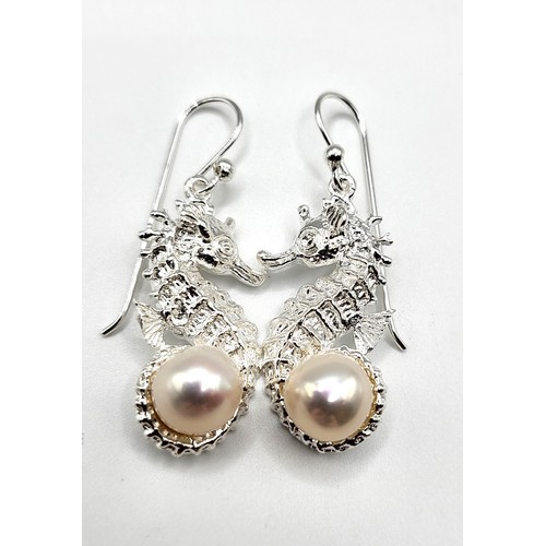 269 - A pair of silver earrings in the form of seahorses, each set with a pearl, approximately 3 cm long, ... 