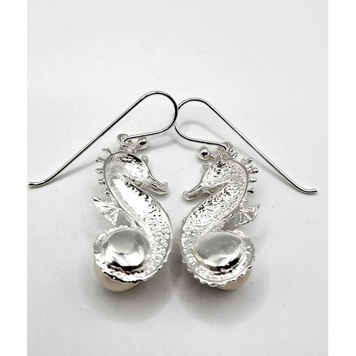 269 - A pair of silver earrings in the form of seahorses, each set with a pearl, approximately 3 cm long, ... 