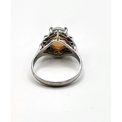 281 - A platinum, diamond, and opal ring, set with an oval cabochon opal, flanked with three small diamond... 