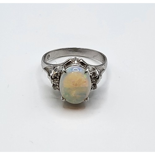 281 - A platinum, diamond, and opal ring, set with an oval cabochon opal, flanked with three small diamond... 