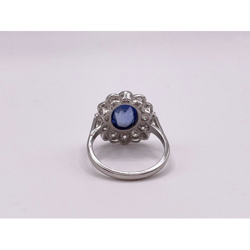 286 - A platinum, diamond, and sapphire cluster ring, set with a mixed oval-cut sapphire within a border o... 