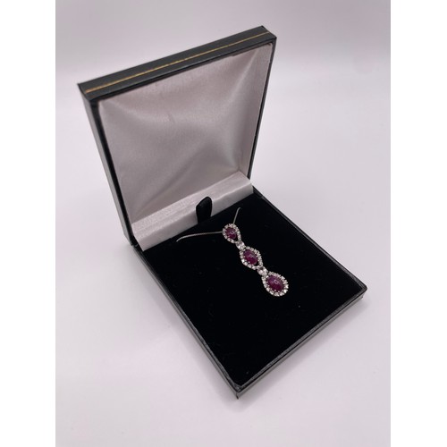 287 - An 18ct white gold, diamond, and ruby pendant, set with three cabochon rubies, within diamond border... 