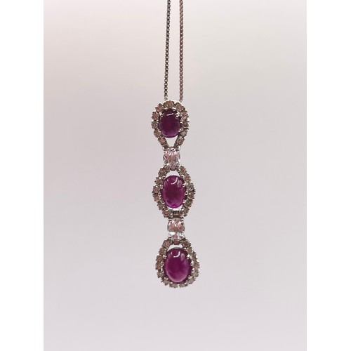 287 - An 18ct white gold, diamond, and ruby pendant, set with three cabochon rubies, within diamond border... 