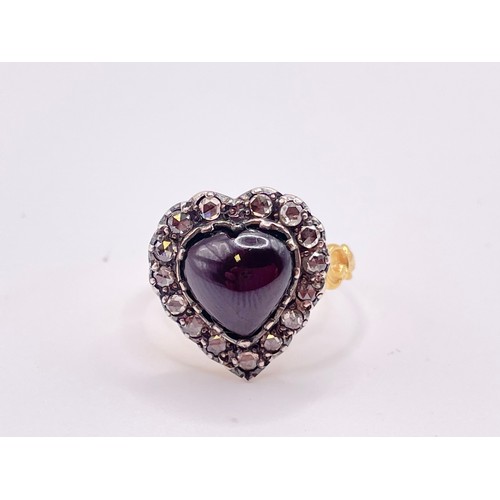 293 - A diamond and garnet ring, in the antique style, set with a heart-shaped cabochon garnet, within a b... 