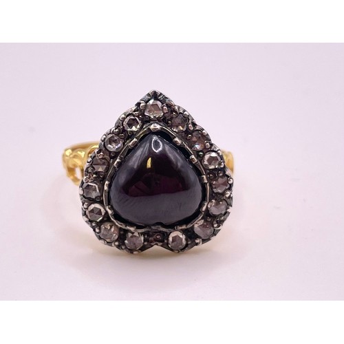 293 - A diamond and garnet ring, in the antique style, set with a heart-shaped cabochon garnet, within a b... 