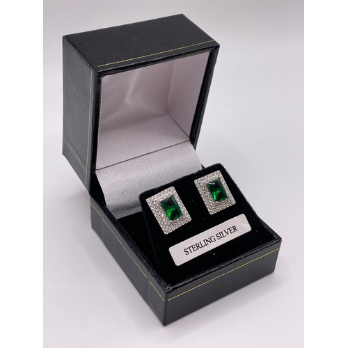 297 - A pair of silver and green cubic zirconia earrings, set within a double border of round-cut white st... 