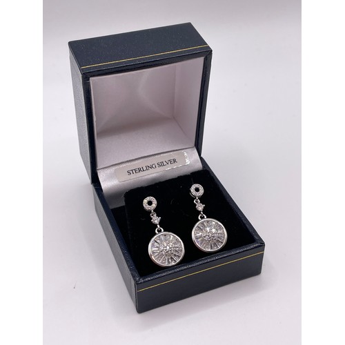 298 - A pair of silver and cubic zirconia drop earrings, set with round and tapered baguette-shaped stones... 