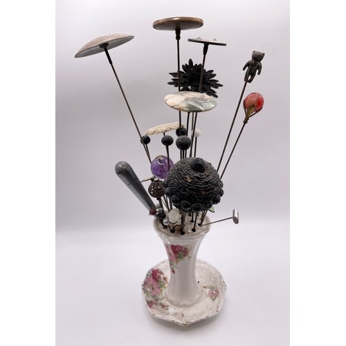 300 - A ceramic hat pin holder containing various 19th and 20th hat pin examples, including an amethyst be... 