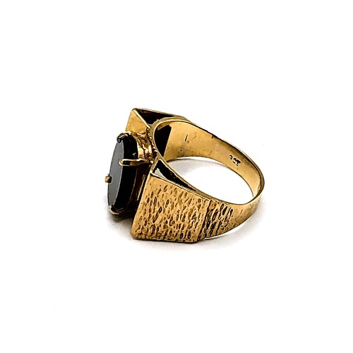 278 - A yellow metal and black onyx ring, with raised pyramid detail to shoulders, centred with an oval on... 