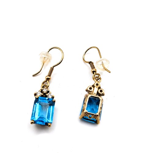 287 - A pair of yellow metal, diamond, and blue topaz earrings, each set with a rectangular-cut topaz meas... 