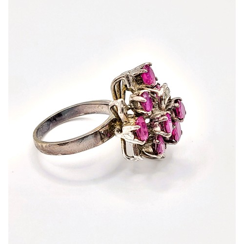 293 - A ruby cluster ring, set with mixed cut rubies, with leaf motif detail inset with small white stones... 